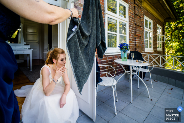 Uma imagem de casamento estilo documentário Luebeck mostrando um momento em que a noiva está fumando