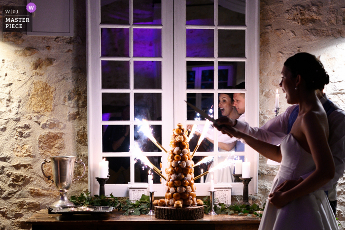 A documentary wedding photographer at the Chateau de la Couronne captured this picture of Cake cutting time With fireworks of course