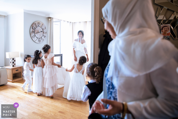 Een topdocumentaire trouwfotograaf uit Lyon creëerde dit beeld van De kleine bruidsmeisjes achter de bruid en een gast kijkt naar deze scène