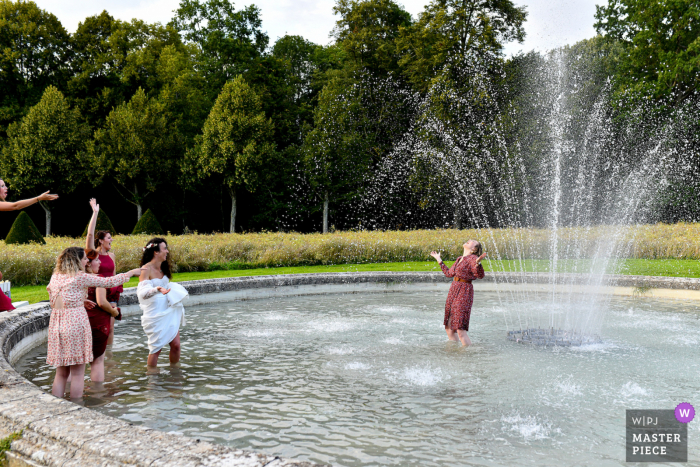 A France documentary wedding photographer captured this picture of the The bride and her best friends playing together during the cocktail hour in a water fountain A France documentary wedding photographer captured this picture of the The bride and her best friends playing together during the cocktail hour in a water fountain