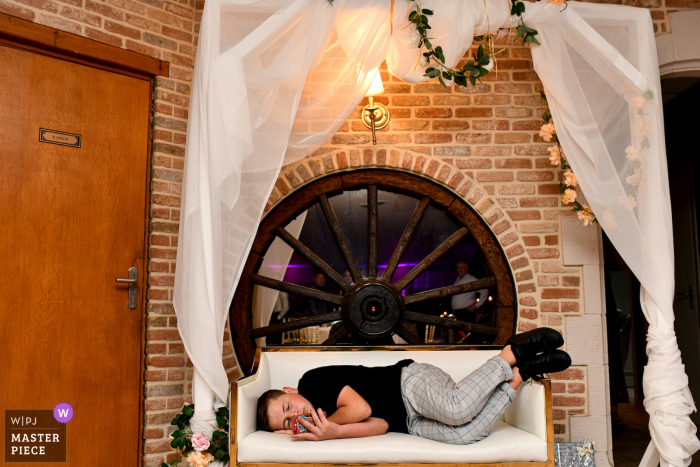 A Lille documentary wedding photographer captured this moment showing a young boy who is bored during the wedding party