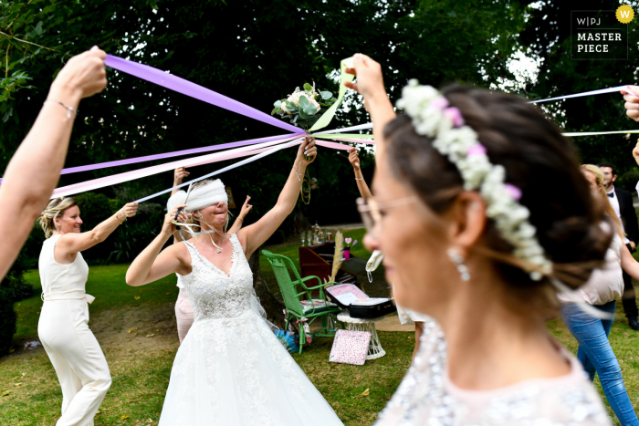 Uma imagem de casamento no estilo documentário da França, mostrando um momento na recepção ao ar livre do concurso de buquê de casamento