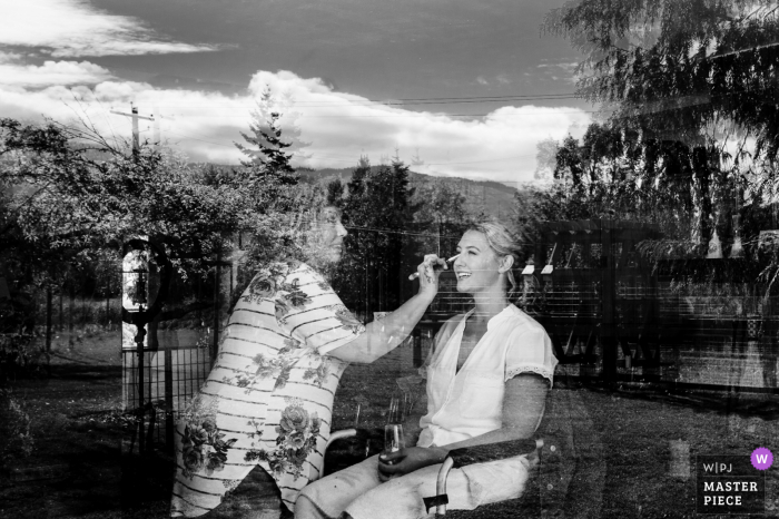 A top Missouri wedding photojournalist created this image of the Bride getting ready at home with a window reflection in BW