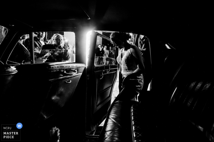 A wedding photojournalist in Missouri captured this moment in BW of the Bride getting into car A wedding photojournalist in Missouri captured this moment in BW of the Bride getting into car