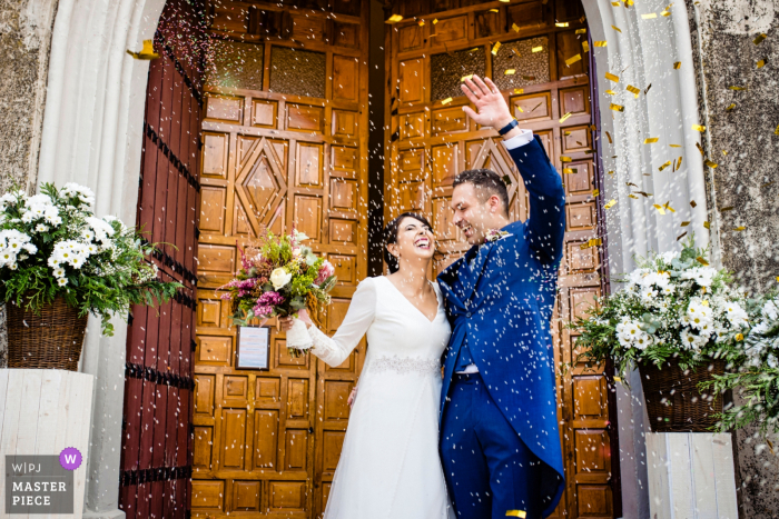 A top wedding photojournalist at Iglesia de Santa María, Arjona in Jaen created this image showing Pure happiness on the faces of the bride and groom as they exit the doors