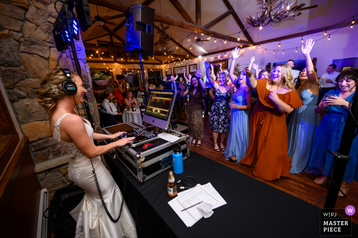 Um documentário fotógrafo de casamento em Estes Park capturou este momento de uma noiva assumindo a cabine do DJ para seus convidados