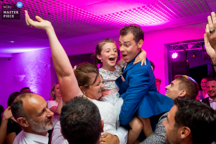 Ein Top-Hochzeits-Fotojournalist aus Frankreich hat dieses Bild eines jungen Mädchens kreiert, das von seinen verrückten Freunden mit ihrem Vater hochgehoben wird