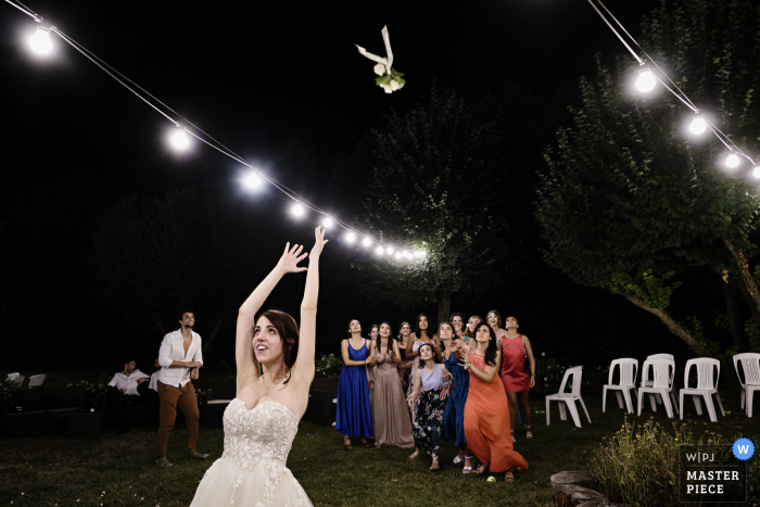 Dokumentalny fotograf ślubny Cesenatico uchwycił ten moment w Villa delle Rose, pokazując pannę młodą rzucającą bukiet kwiatów w nocy na zewnątrz