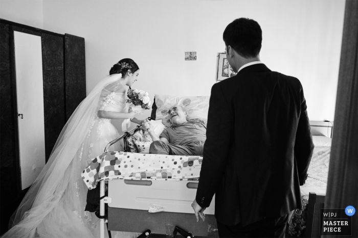 Une image de mariage de style documentaire de Cesenatico montrant un moment lors d'une visite au grand-père de la mariée après le mariage