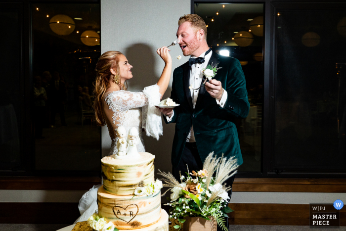 A Snowmass, Colorado documentary-style wedding image showing A chunk of cake falls from the fork as the bride feeds the groom