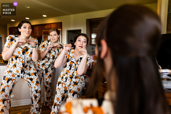 Ein dokumentarischer Hochzeitsfotograf in Golden, Colorado, hat dieses Bild aufgenommen, auf dem die Brautjungfern in passenden Pyjamas die Braut während ihres Friseurtermins unterhalten