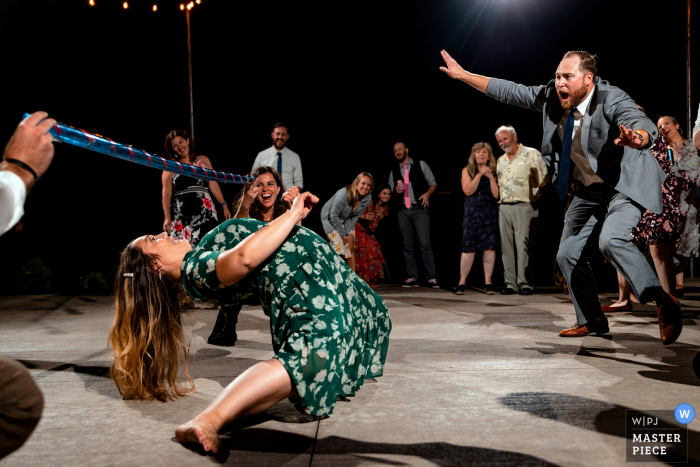 Um importante fotojornalista de casamento em Montrose, Colorado, criou esta imagem de Um convidado de casamento celebrando enquanto outro convidado conclui o limbo