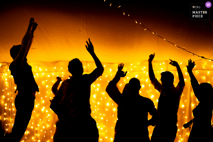 View this dramatic Oxford wedding image at The Perch in the UK of silhouetted guests dancing against fairy lights