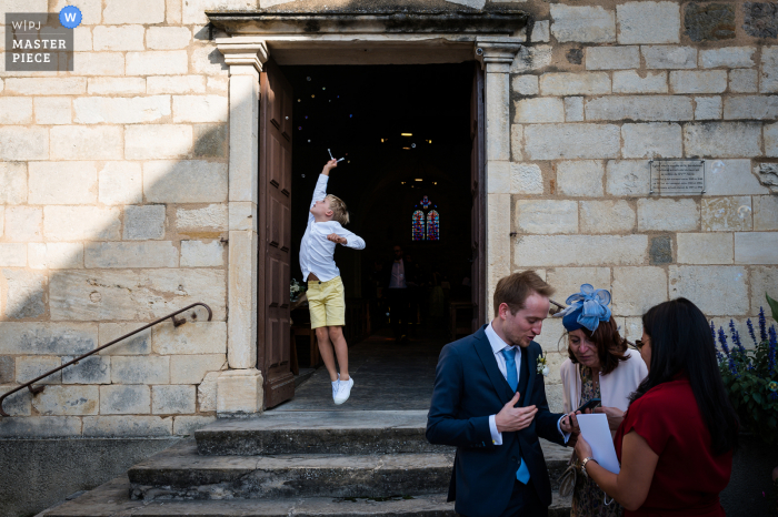 Vea este excelente ejemplo de la mejor fotografía de bodas del mundo de Lyon, Francia, en el lugar de la ceremonia con un niño pequeño que salta