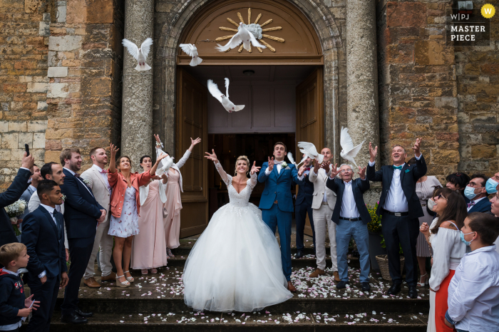 Uma imagem de casamento no estilo documentário de Lyon mostrando um momento com a noiva, o noivo e as pombas