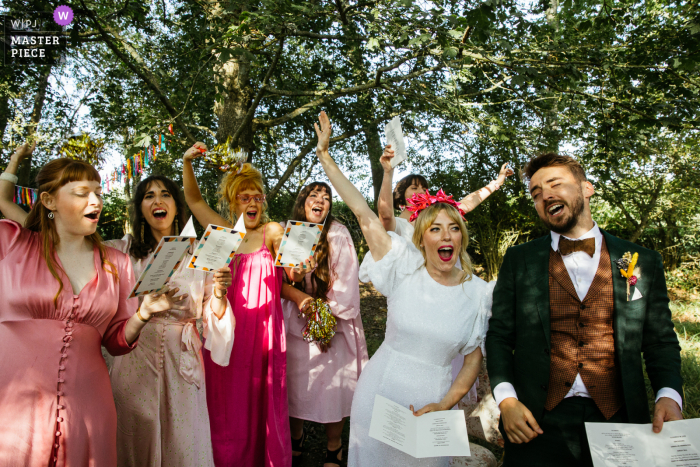 Un destacado fotógrafo de reportajes de bodas de Sussex en Yogaurt Rooms capturó esta imagen de un canto durante la ceremonia al aire libre bajo los árboles.