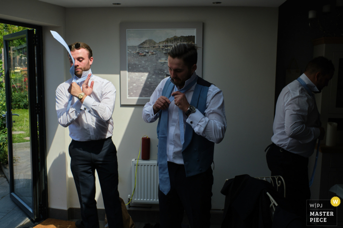 A top Leicestershire wedding reportage photographer in Rothley captured this picture of One of the groomsman shows off his tie tying skills