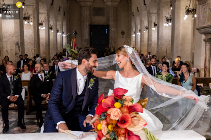 Een trouwfoto in documentaire-stijl van Siracusa die een moment toont bij Chiesa Cattedrale Natività di Maria Santissima die toont Deze bruid is zo gelukkig dat ze op dit moment graag met de bruidegom zou willen vliegen