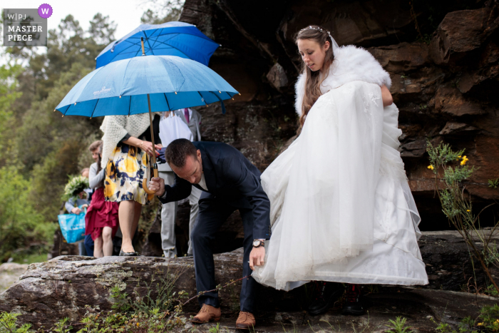 Um fotógrafo francês de documentários famosos de casamentos de Cévennes criou esta imagem. Enquanto caminhava na natureza, a noiva pegou seu vestido em uma amoreira-preta, um convidado vem em seu socorro