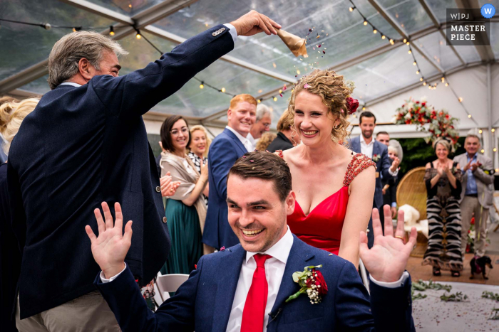 Een top trouwfotojournalist van Heenvliet bij De Hoecksack maakte deze afbeelding waarop het bruidspaar wordt bedekt met confetti na de ceremonie