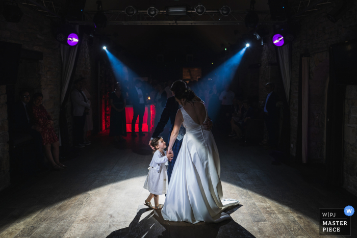 View this dramatic Quimper, France wedding image of the First dance under spotlights with a young girl View this dramatic Quimper, France wedding image of the First dance under spotlights with a young girl