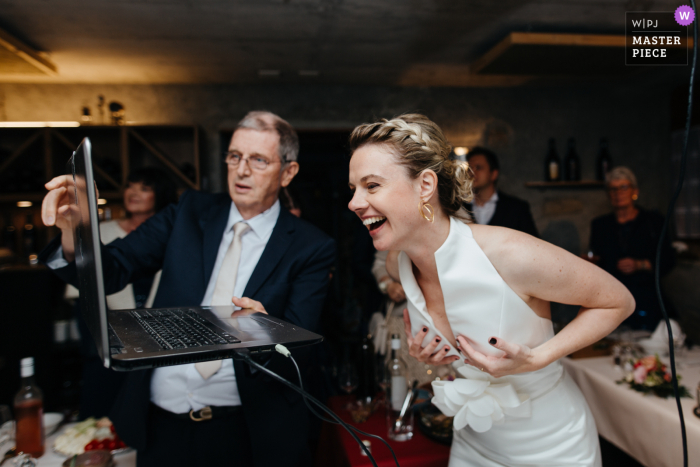 Uma imagem de casamento em estilo documentário de Lausanne mostrando um casal Suisse em uma sessão de vídeo virtual usando um laptop