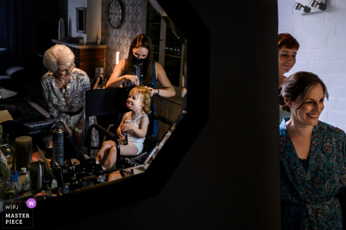 A Flanders wedding reportage photographer captured this moment of the girls getting ready for the ceremony