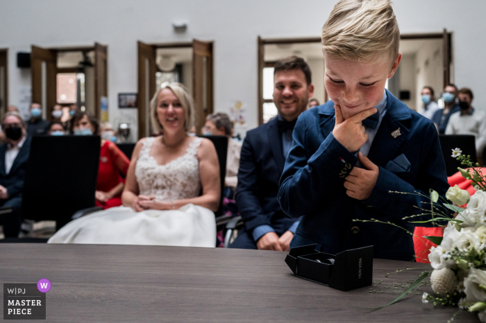 Een topfotograaf in het gemeentehuis van een Belgische trouwreportage maakte deze foto van de ringdrager die de ringen inspecteerde tijdens de ceremonie