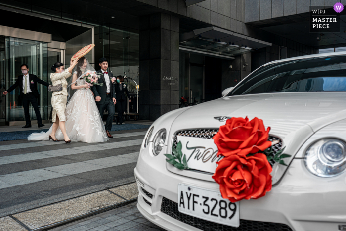 Um fotojornalista renomado de casamento do Le Méridien Taipei criou esta imagem de A noiva e o noivo estavam saindo do hotel e prontos para entrar na limusine