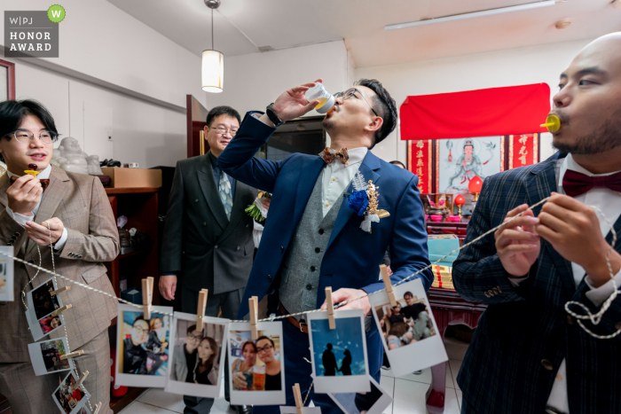 A top Taiwan wedding photojournalism example from a Taipei wedding event with The groom drinking juice from a baby bottle of his son during door game ceremony