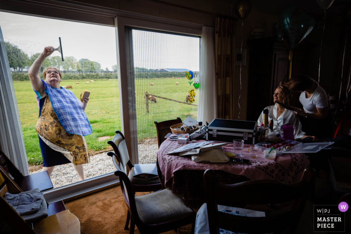 View this comical Netherlands wedding image of a window cleaner at home during the bride getting ready session