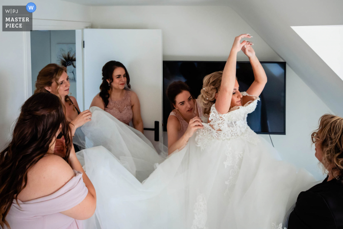 A Netherlands wedding photojournalist captured this moment at home getting ready for the bride in her dress