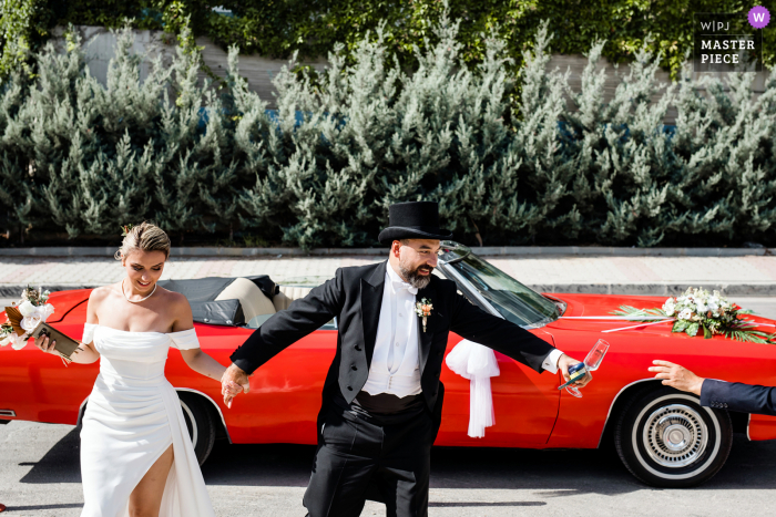 A top documentary wedding photographer from Istanbul created this image showing the arrival of the bride and groom in a convertible red sports car