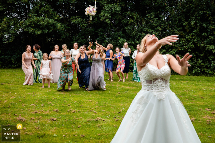 A North Brabant wedding reportage photographer captured this moment at the outdoor reception venue	during the bride tossing of the bouquet