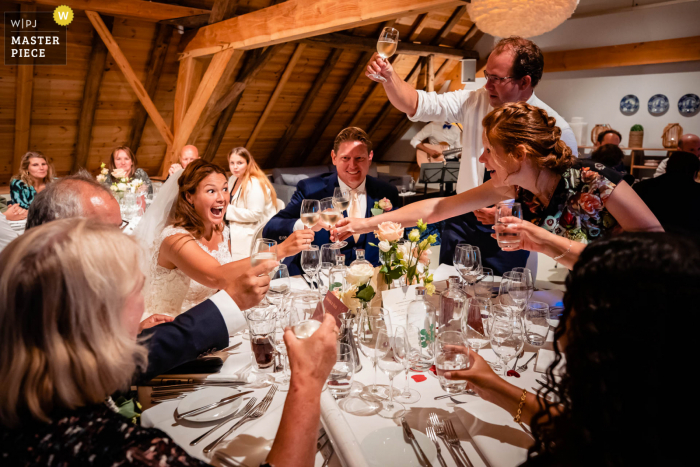 A Netherlands documentary wedding photographer captured this moment at the reception dinner venue toast