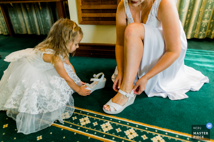 A Bulgaria documentary wedding photographer captured this moment at the Grand Hotel Sofia showing little princess helps to prepare the bride with her shoes