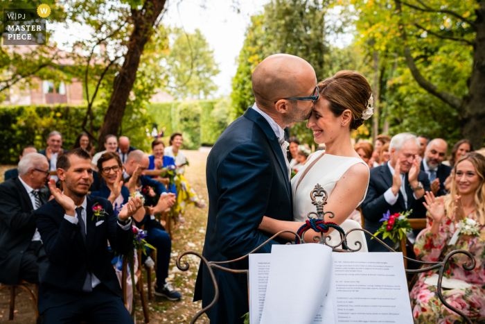 A wedding photojournalist at La Brunelde Fagagna in Udine captured this moment of the First kiss as husband and wife A wedding photojournalist at La Brunelde Fagagna in Udine captured this moment of the First kiss as husband and wife