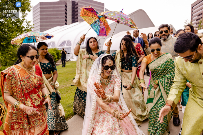 A Illinois documentary-style wedding image showing a moment at the Westin Hotel Itasca during an Indian ceremony outdoors under umbrellas