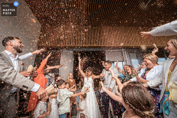 Un photographe de mariage documentaire en France à la mairie a capturé cette photo de la sortie de la mairie, avec des fleurs dans le visage pour les mariés