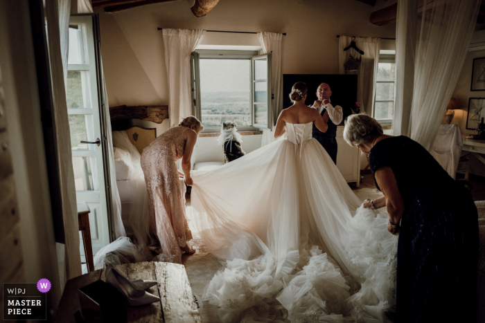 Ein italienischer Top-Dokumentar-Hochzeitsfotograf von Conti di San Bonifacio Gavorrano in der Toskana hat dieses Bild erstellt, das die Vorbereitung der Braut, Mutter, Großmutter, des Vaters und ihres Hundes zeigt