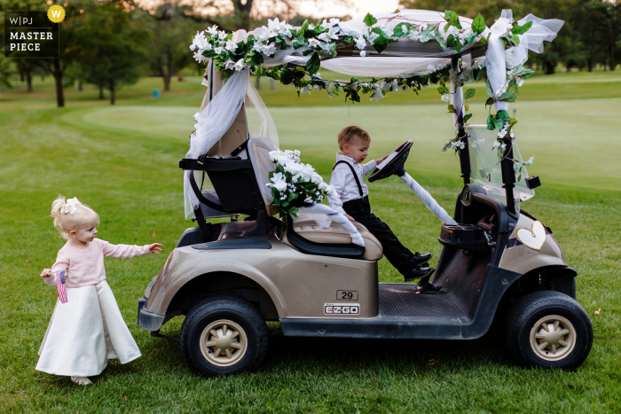 A Chicago wedding photojournalist at the Baringtron Hill Country Club captured this moment showing kids playing on a decorated golf cart A Chicago wedding photojournalist at the Baringtron Hill Country Club captured this moment showing kids playing on a decorated golf cart