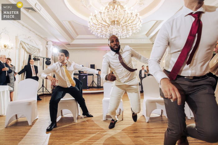 Una imagen de boda de estilo documental de Polonia que muestra un momento en el White Palace Niesiecin de los invitados que participan en la diversión de la boda se levantan de sus asientos para la carrera