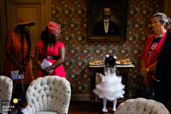 A Netherlands documentary wedding photographer captured this moment at Landgoed Sparrendaal in Driebergen during reception of young flower girl checking out food table