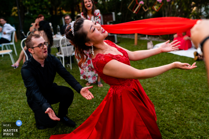 Un fotógrafo de reportajes de bodas de Italia capturó este momento en la Villa Rigatti Fiumicello en Udine de un juego de limbo al aire libre en el césped