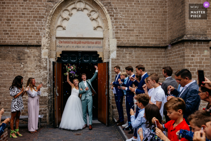 Bekijk dit belangrijke moment in de Nicolaikerk, Utrecht trouwfoto van het bruidspaar dat de kerk verlaat na de ceremonie