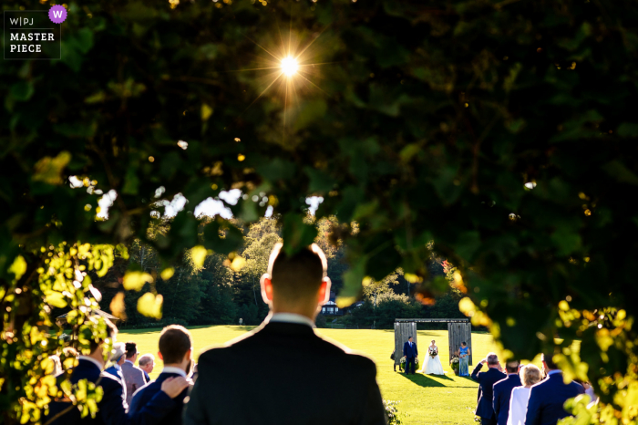 Un photojournaliste de mariage du Vermont a capturé ce moment au Mountain Top Inn de Chittenden montrant Le marié regarde la mariée et ses parents franchir une série de portes et descendre l'allée