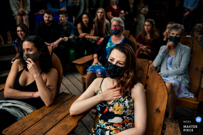 Een trouwfoto in documentairestijl in Indian Lake NY in Timberlock Camp met een moment waarop gasten reageren op een emotioneel moment in de ceremonie