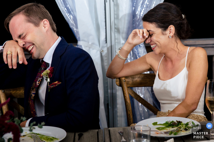 A fotografia documental de casamento de Deer Isle ME em Aragosta Goose Cove foi feita de Os recém-casados ​​se espelhando em risadas na recepção do casamento