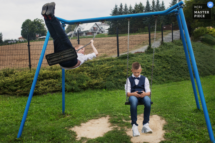 A wedding photojournalist in Krakow captured boys playing on the swings with a mobile device