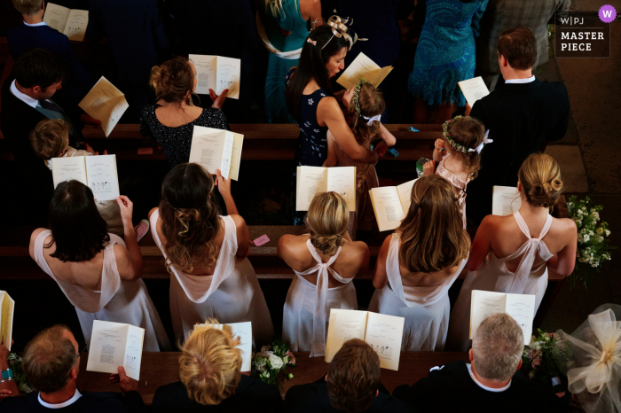 A London wedding reportage photographer captured this View from the choir balcony of bridesmaids during the service